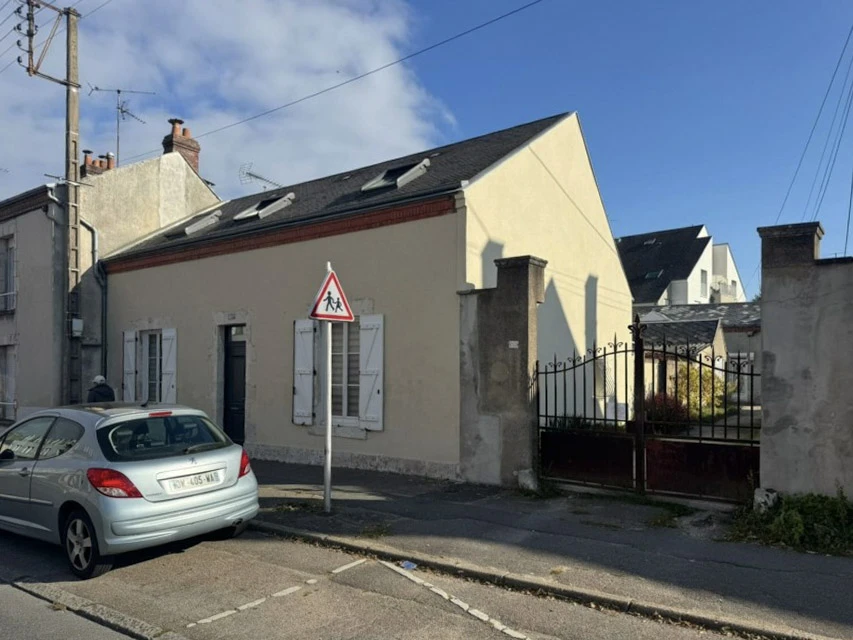 Scène extérieure urbaine avec maison individuelle de plain-pied à façade beige et volets blancs