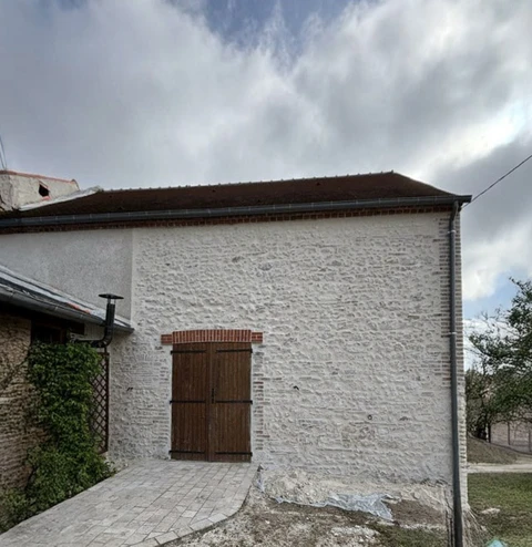 Extérieur d'un bâtiment résidentiel avec mur en pierre calcaire blanche et encadrement de porte en brique rouge