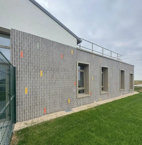 Bâtiment moderne à usage professionnel avec façade en briques grises et accents colorés jaunes et rouges