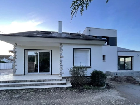 Maison moderne à façade blanche avec portes-fenêtres coulissantes, volets roulants et escalier en pierre