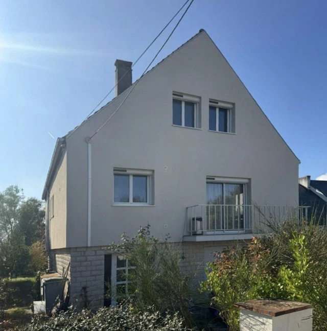 Façade de bâtiment en cours de rénovation avec murs en pierre apparente partiellement recouverts d'enduit blanc écaillé