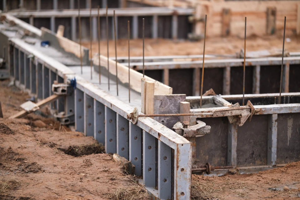 Cave ou sous-sol en construction avec escalier métallique à marches en bois menant à l'étage supérieur