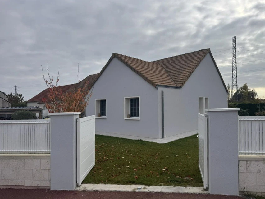 Maison traditionnelle en pierre calcaire avec toiture en tuiles plates, cheminée en brique, mur crépi blanc