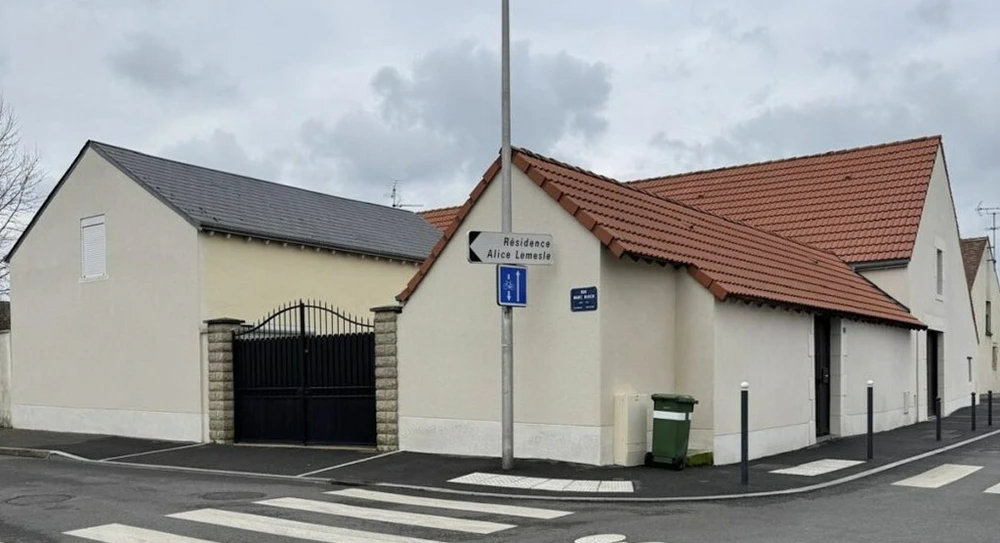 Maison traditionnelle en pierre calcaire avec toiture en tuiles plates, cheminée en brique, mur crépi blanc